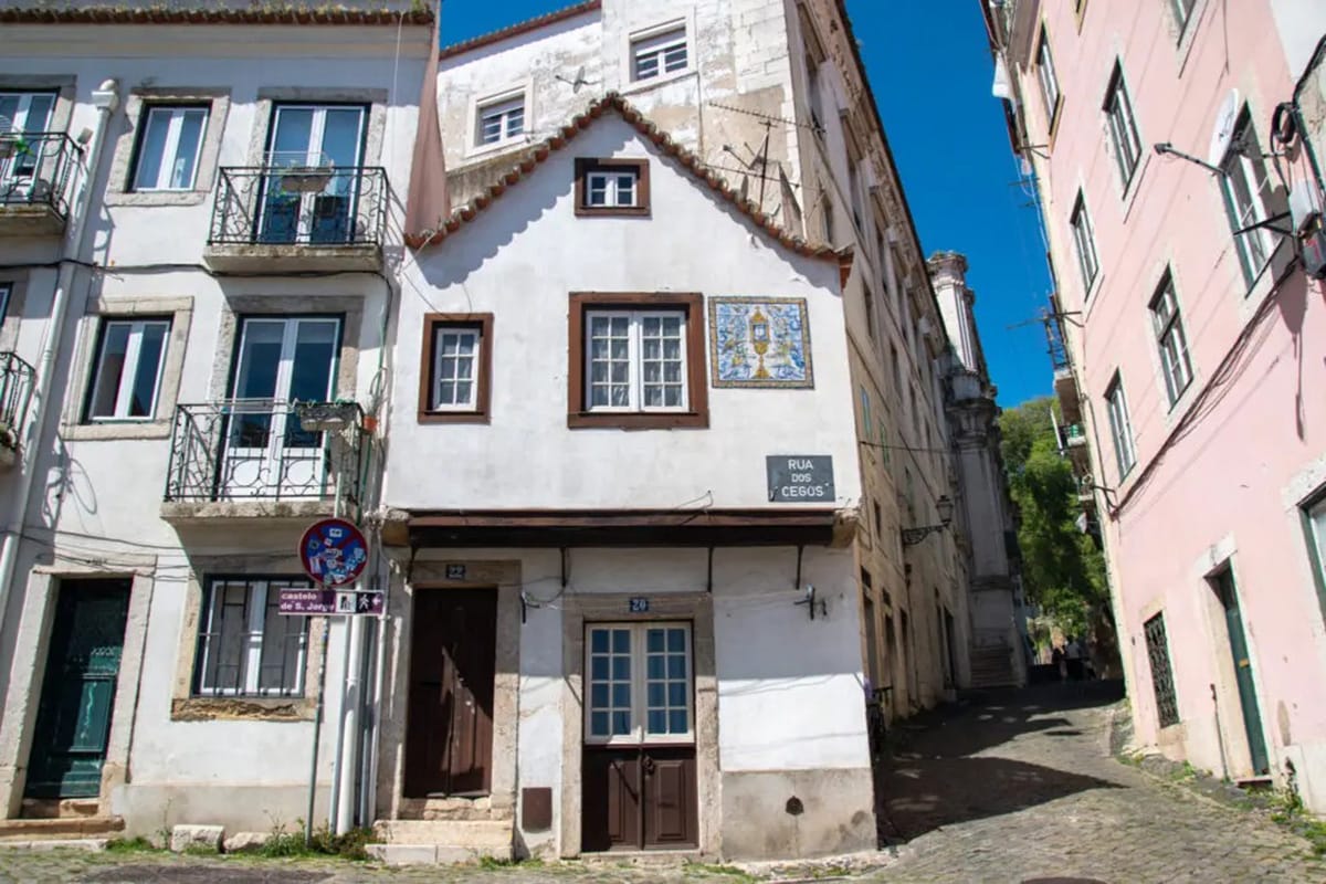 two-story white house near a stone alley.
