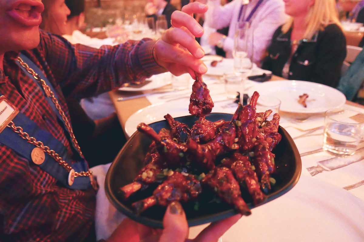 close up of a man taking a marinated duck wing from a platter at The Duck Inn in Chicago.