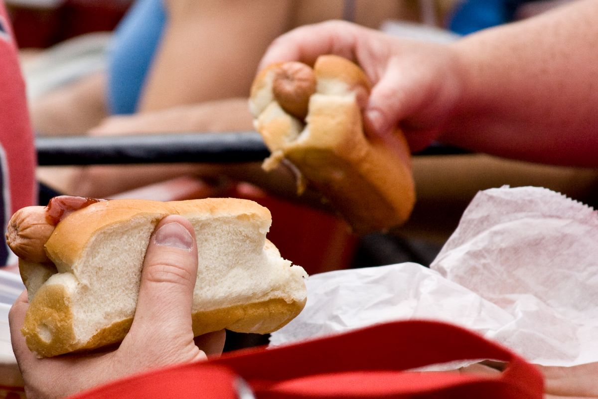 A person holding Boston famous foods: two Fenway Frank hot dogs. 