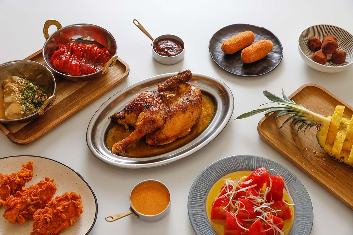 rotisserie chicken, croquettes, and other Spanish food on a white table.