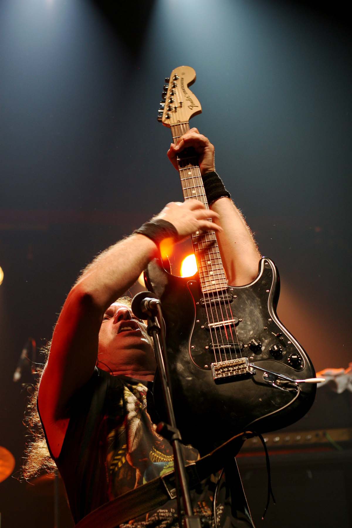 rock musician holding up an electric guitar onstage.
