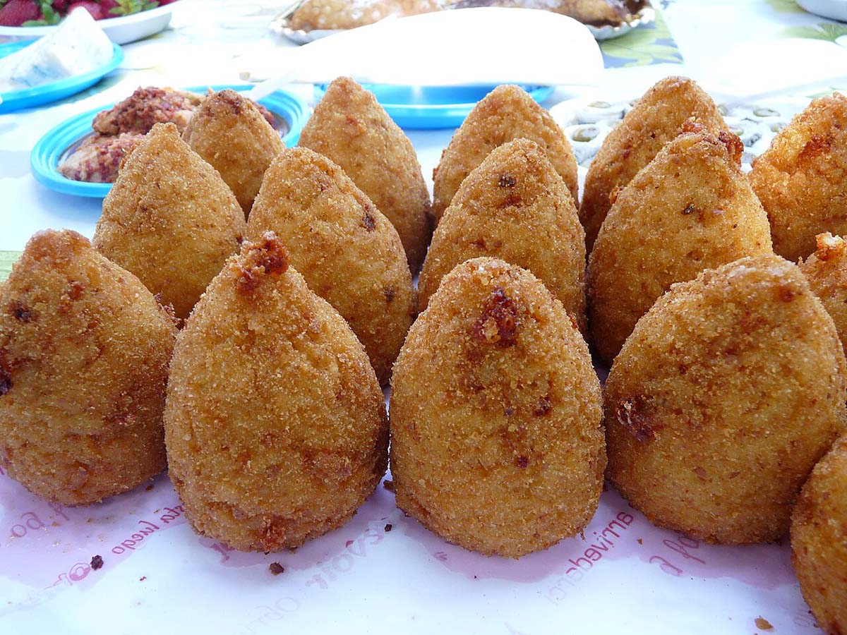 cone-shaped deep fried rice balls on a paper-lined platter.