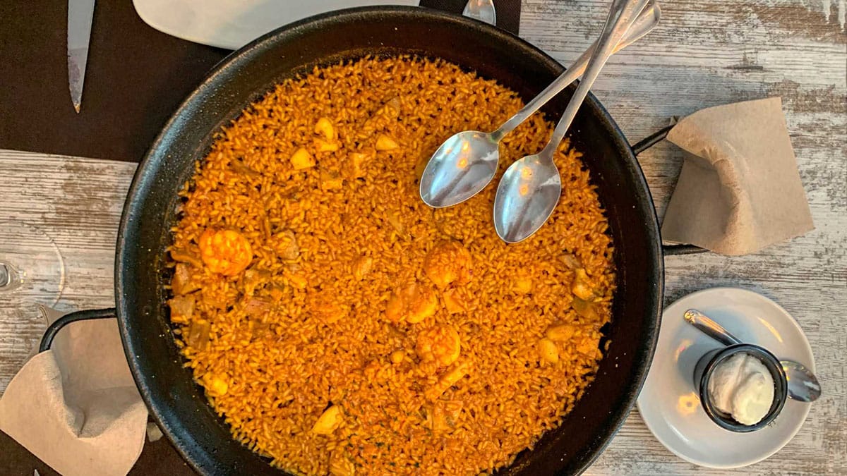 broad, shallow pan with cooked rice and shrimp in a thin layer.