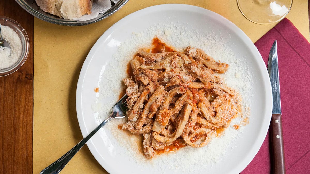 white plate of offal with a fork and knife on a table with a red napkin.