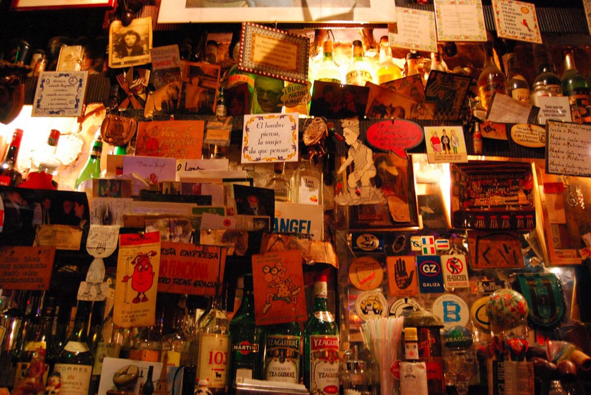 a wall of photos, cards, and mementos behind a bar.