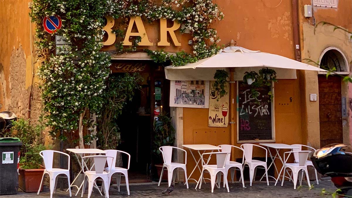 small Italian bar with a white flowering vine growing on the building.