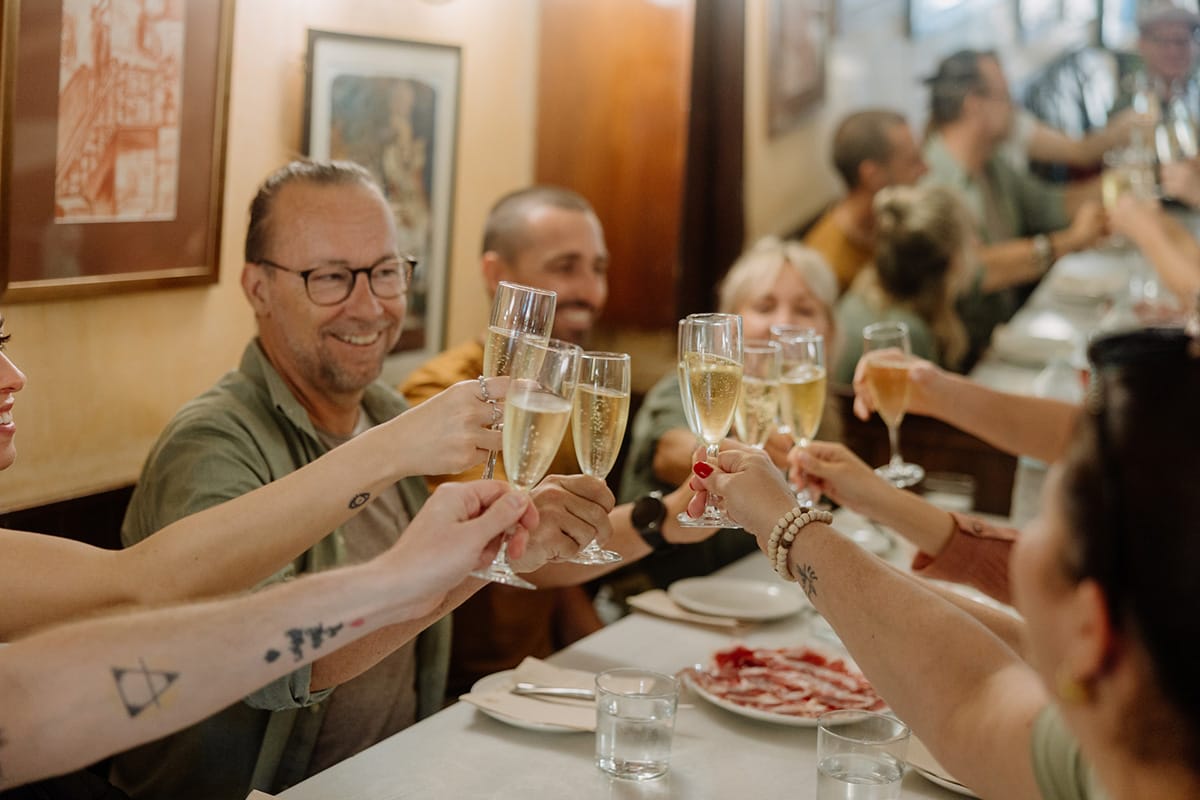 people eating tapas at a table and toasting with cava.