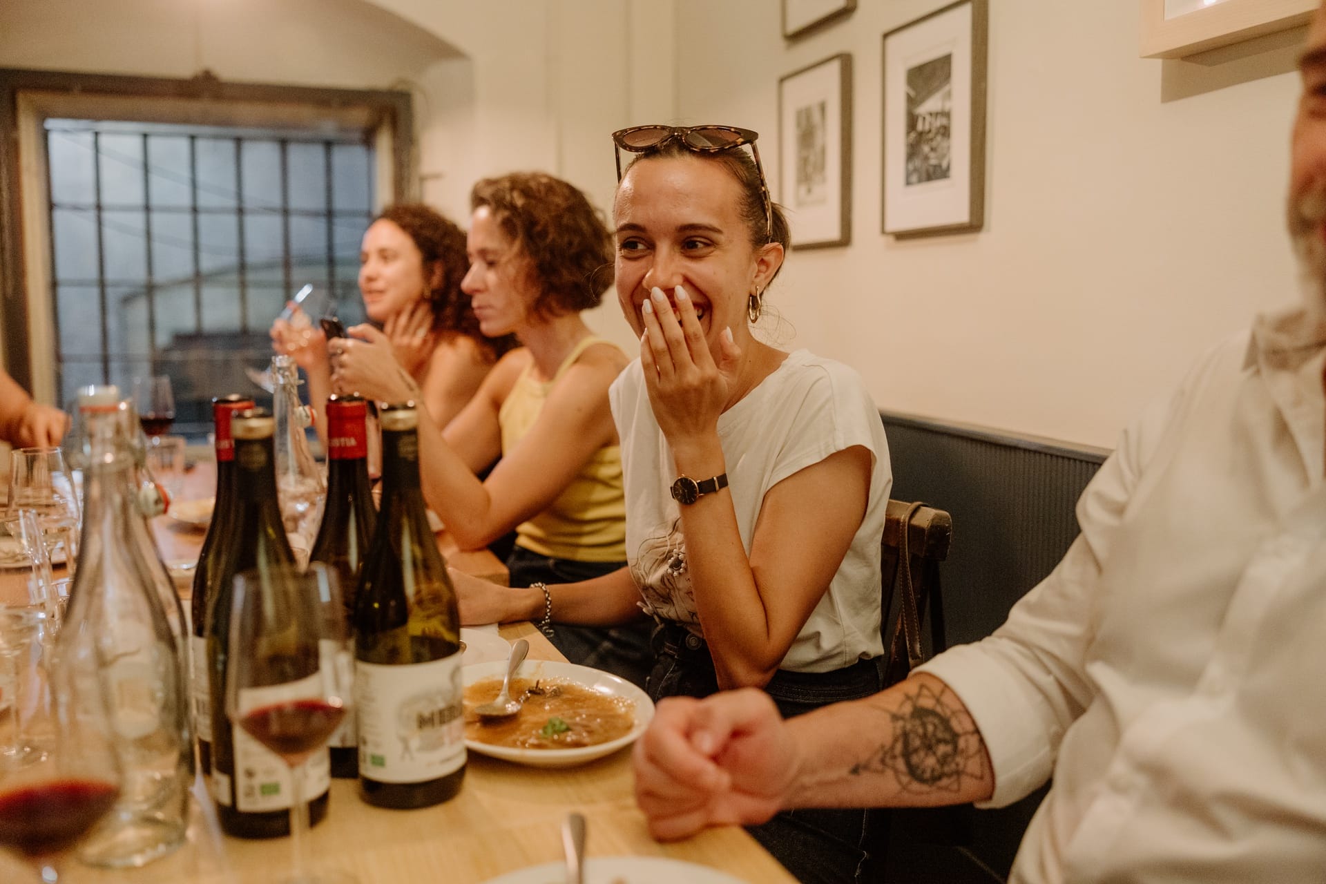 people sitting at a long table eating tapas and drinking wine.