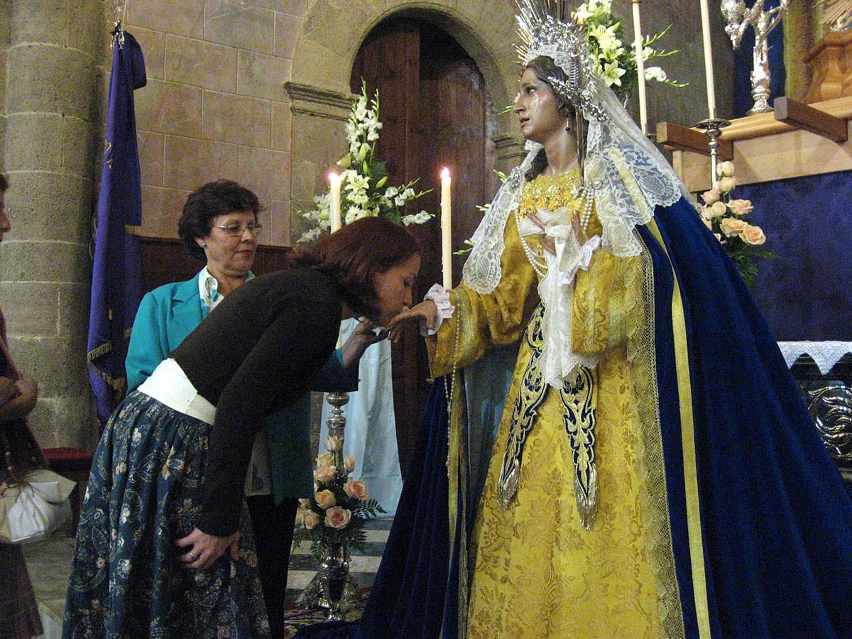a lady kissing the hand of a female sculpture dressed in a fancy dress and crown.