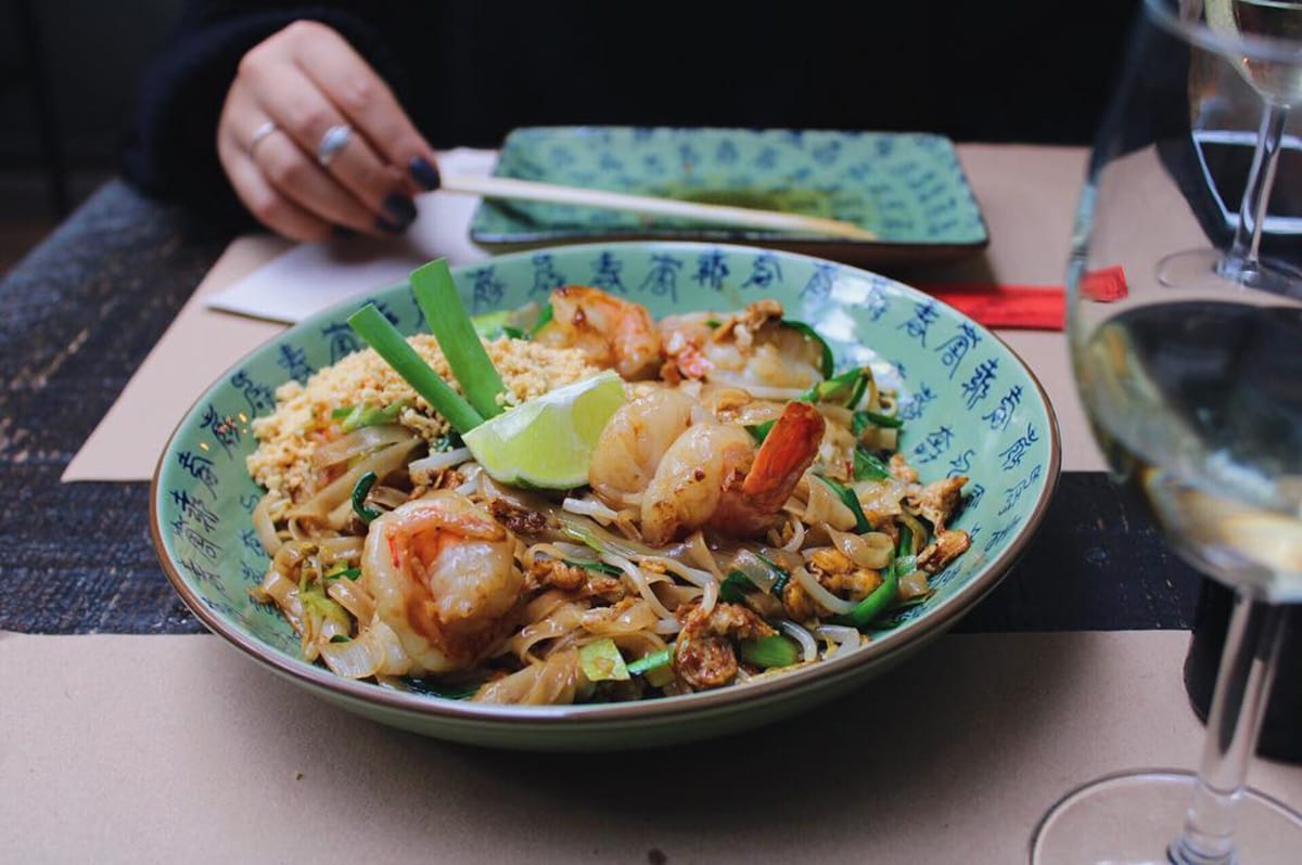 large bowl of Asian food garnished with a lime wedge and green onion.