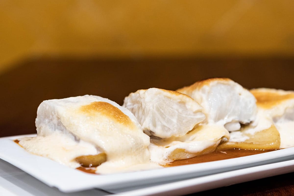 white platter of codfish with a sauce on top.