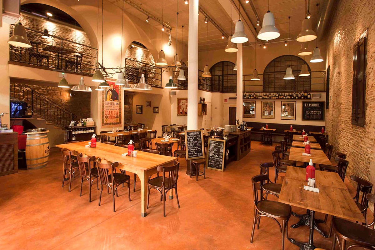 two-story interior restaurant with hanging lights, tables, and chairs.