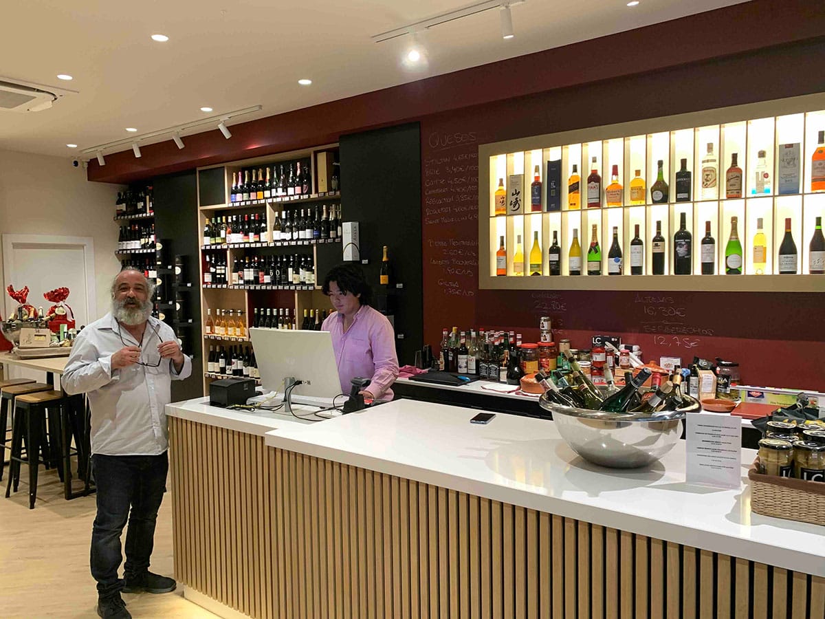 woman talking to a man at a counter in a wine shop.