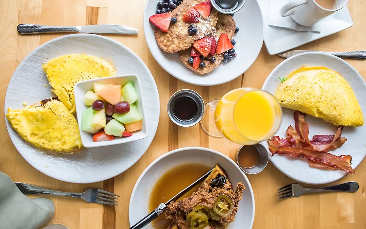 plates of brunch foods, such as fruit, omelettes, pancakes, and fruit.