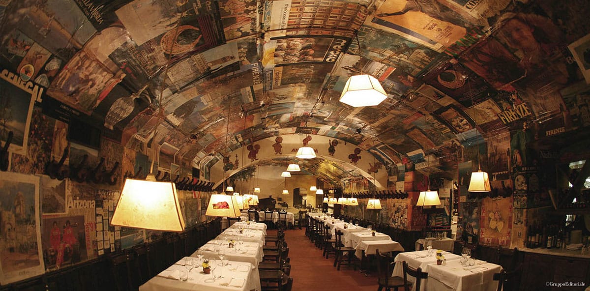rows of white-covered tables and chairs under an arched ceiling.