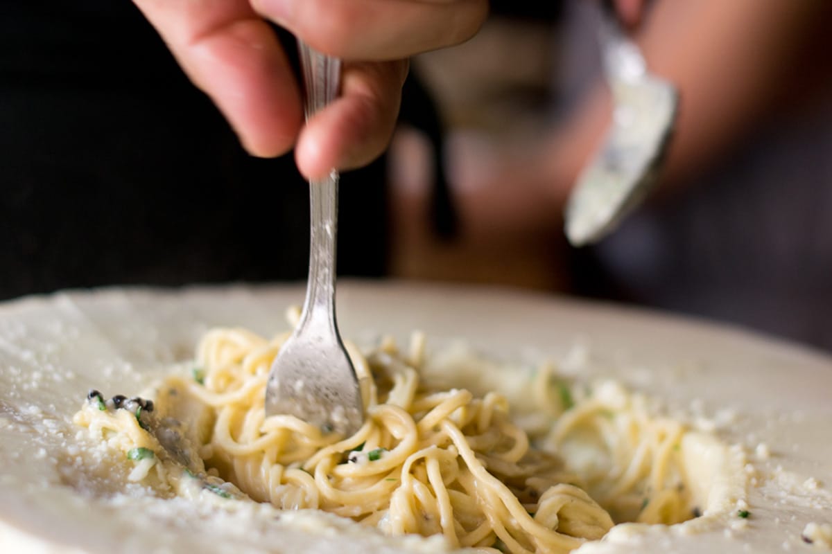 person tossing cacio e pepe in the center of a cheese wheel.