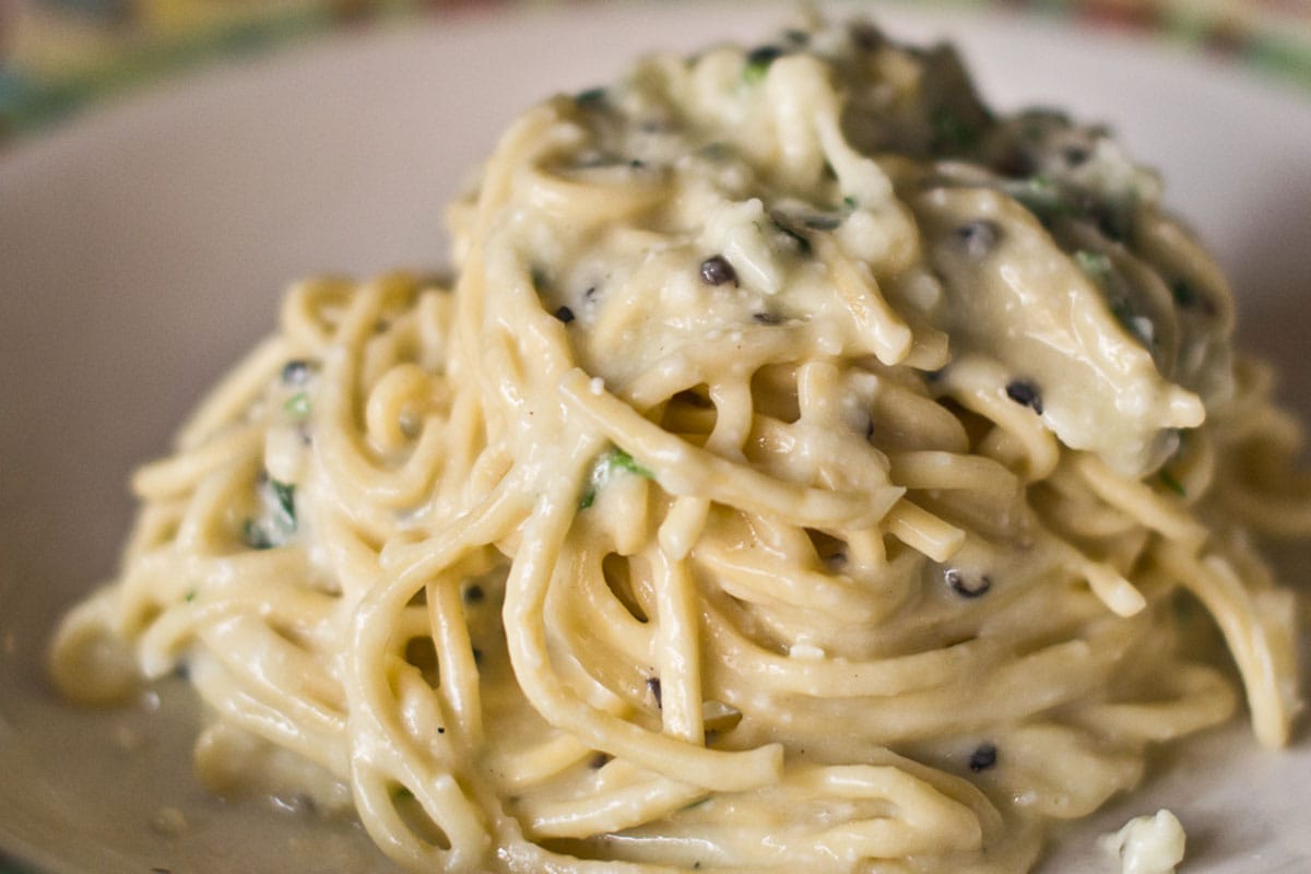 pile of cacio e pepe with black pepper on a white plate.