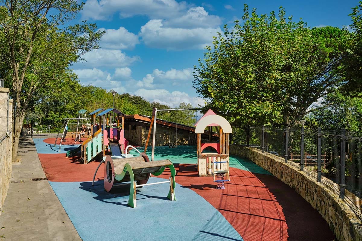 wooden playground in a tree-lined park.