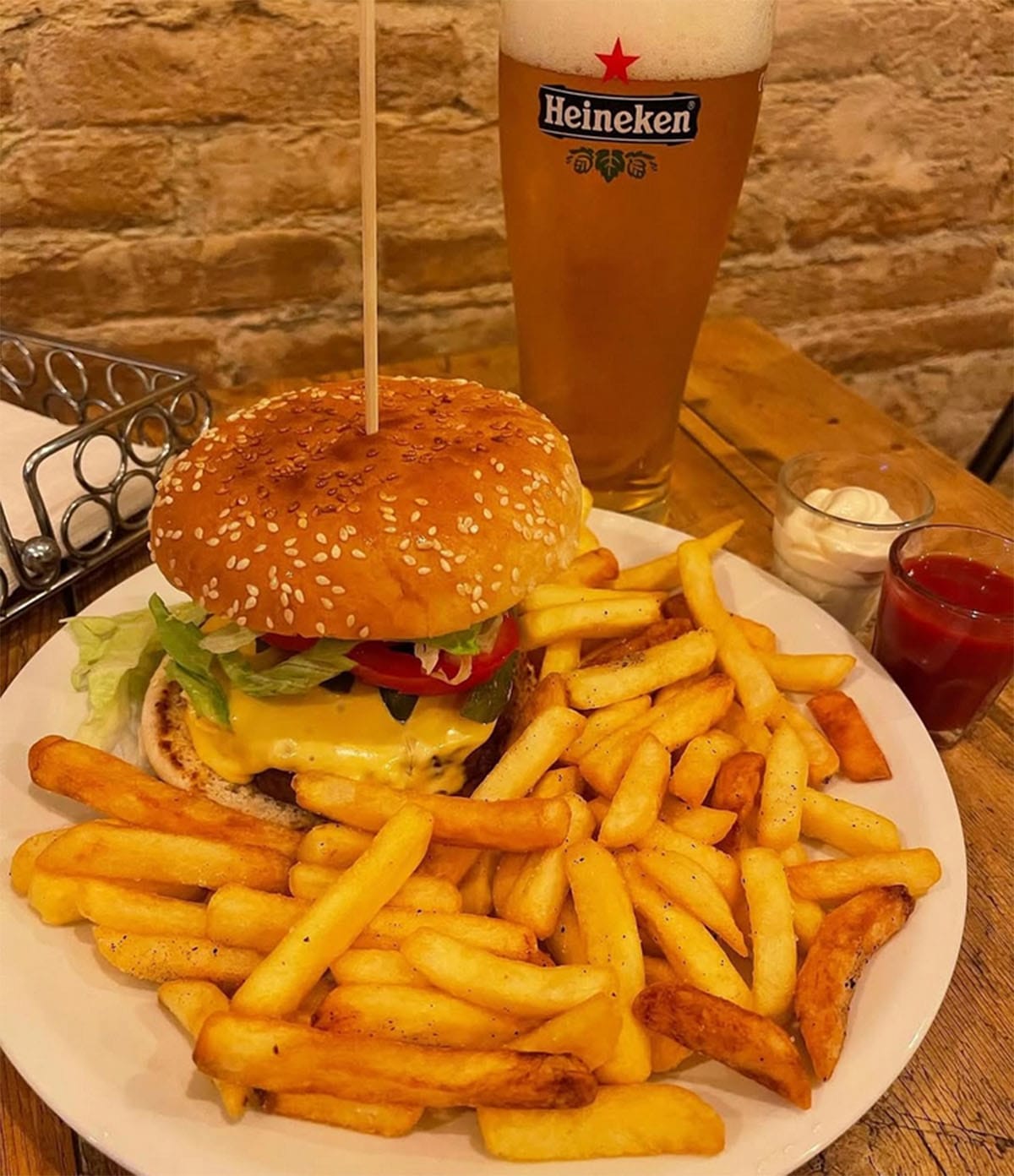 plate of a large hamburger with French fries and a beer.