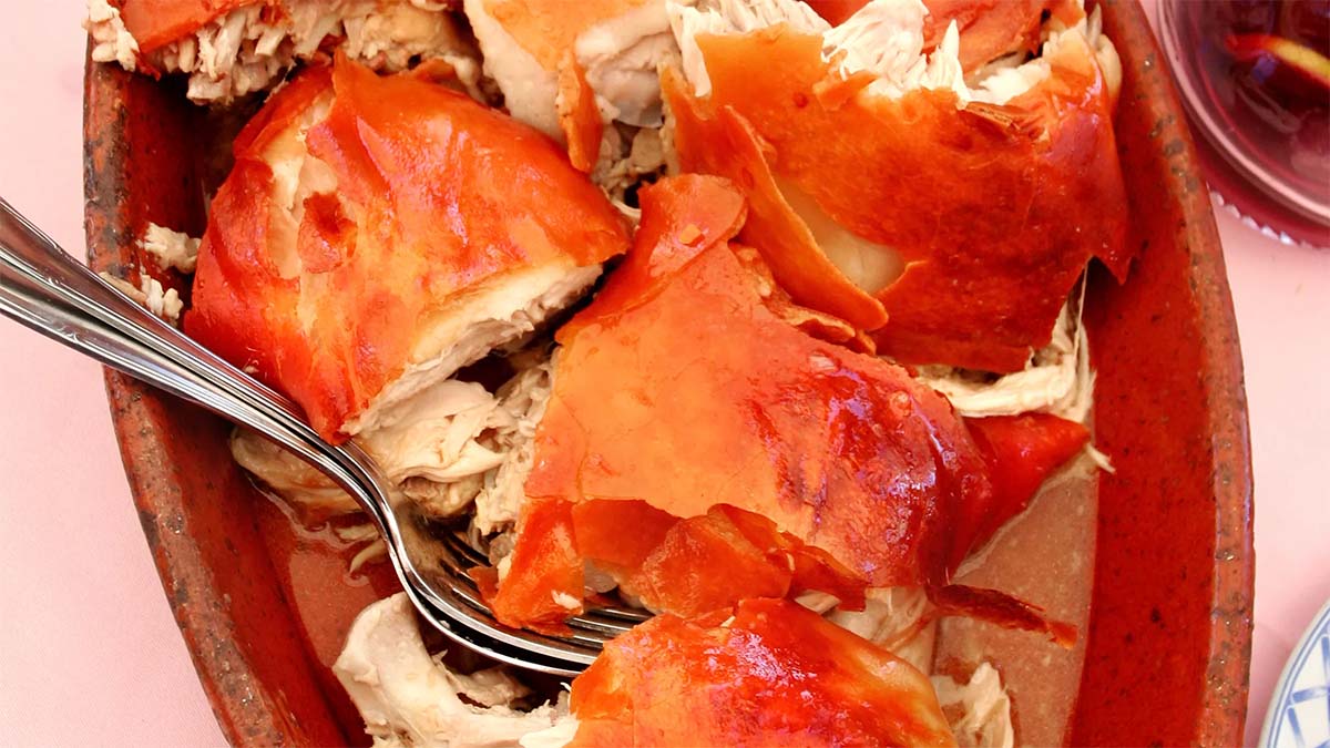 clay dish filled with pieces of roasted pork with crispy skin.