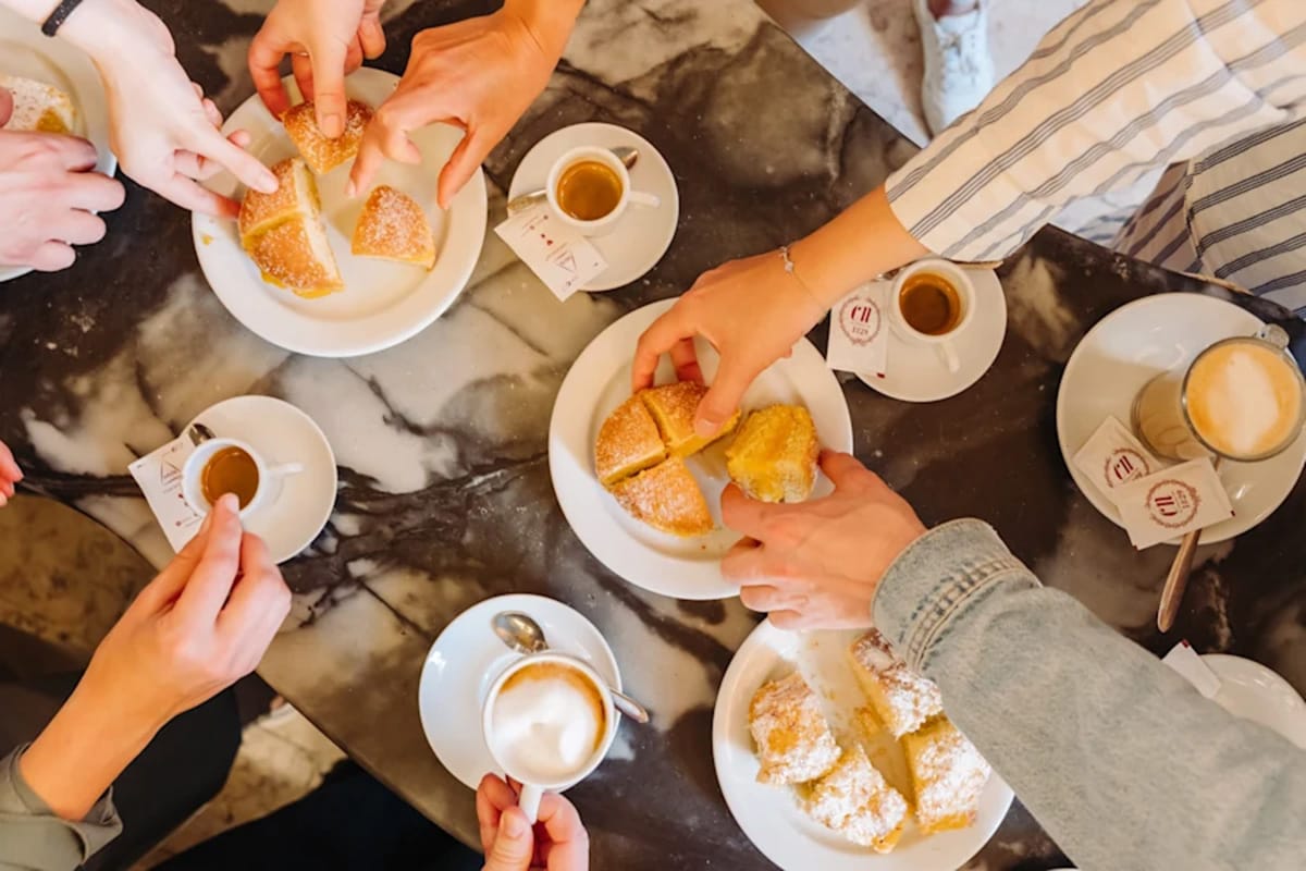 people enjoying sweet bread and coffee at a marble table.