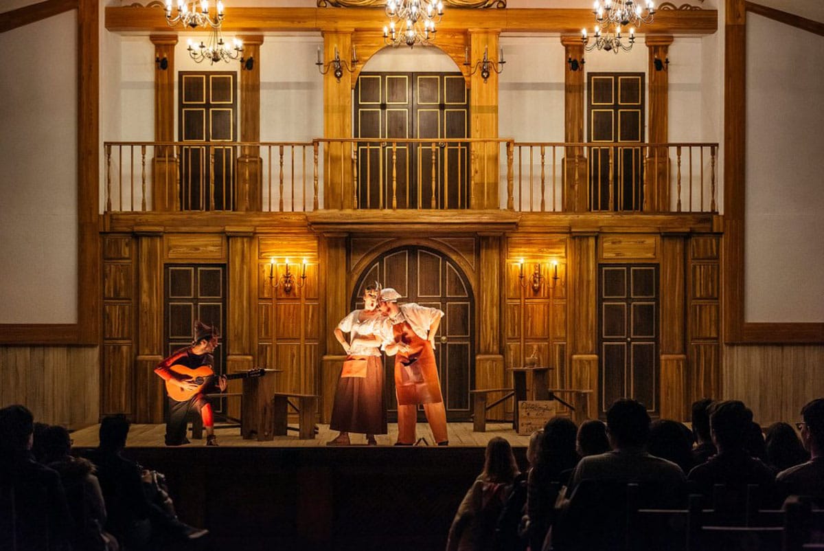 three performers on stage with a detailed set behind them.