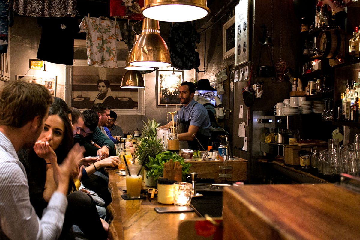 people enjoying drinks at a wooden bar.