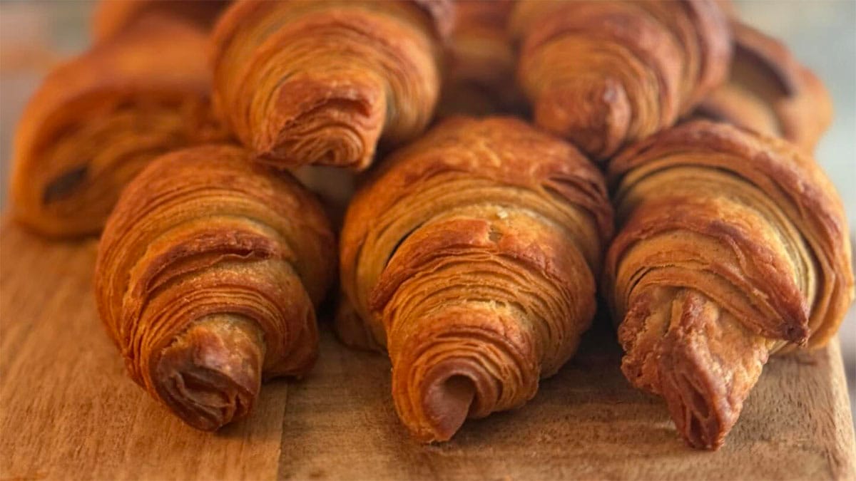 stack of flaky, buttery croissants on a wooden cutting board.