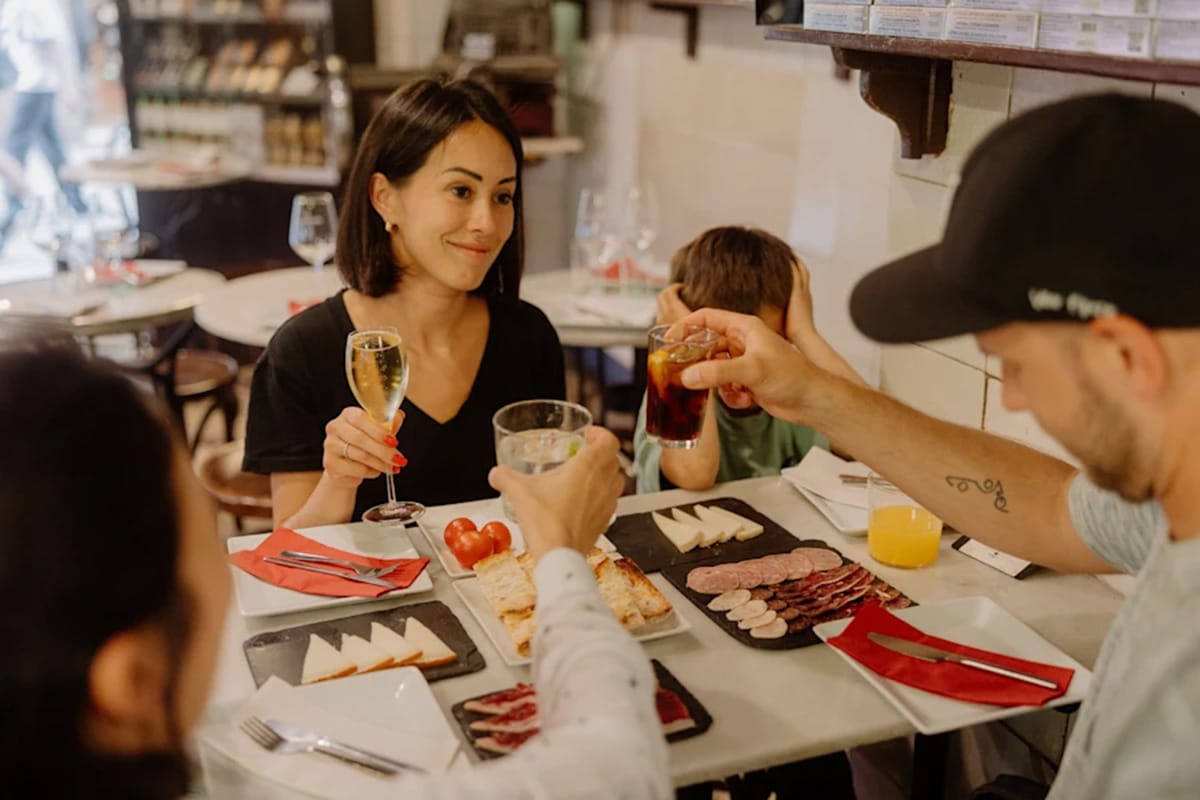 man and woman toasting with glasses of wine while a boy sits with them at the table.