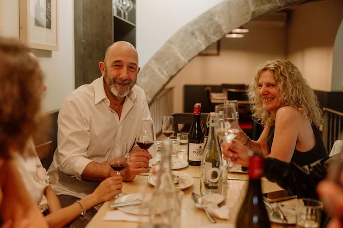 man and woman at a table with wine glasses and smiling.