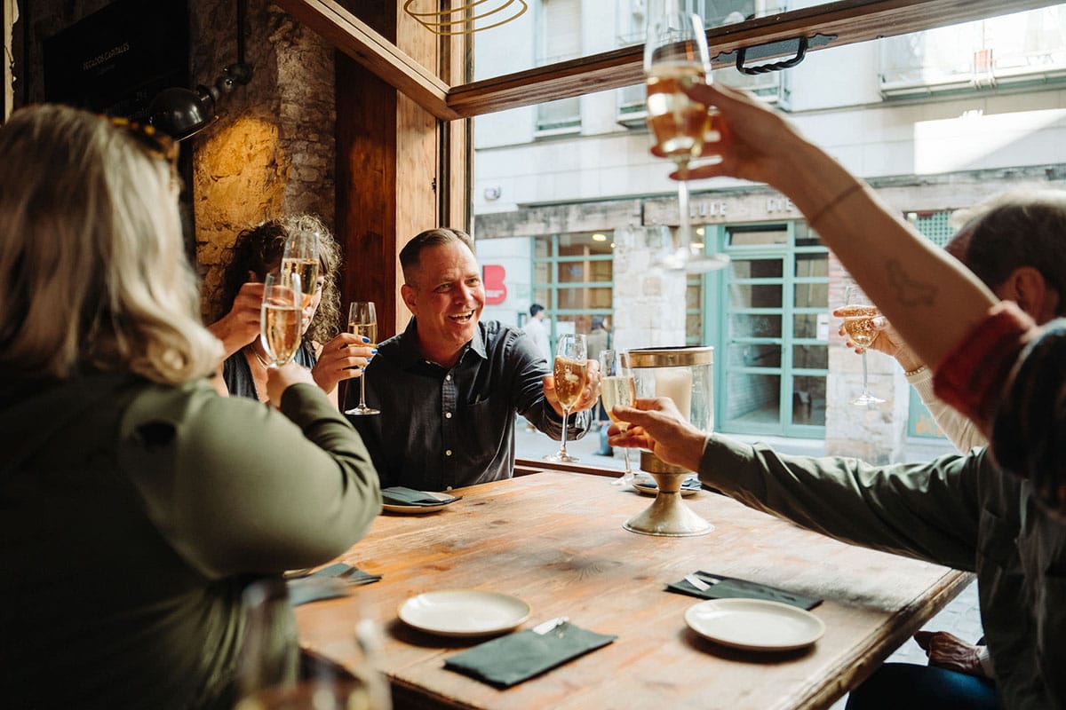 people toasting with cava near a window in a restaurant.