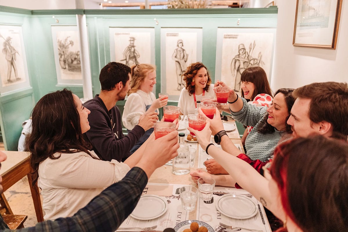 people sitting at a dinner table and toasting with drinks.
