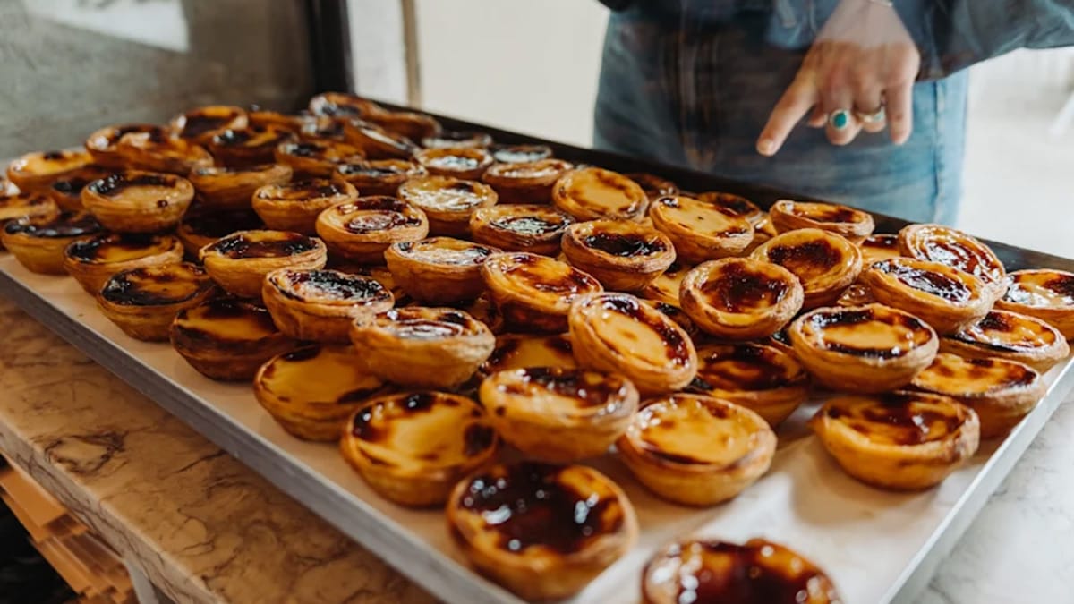 large tray of stacked custard tarts in a bakery window.