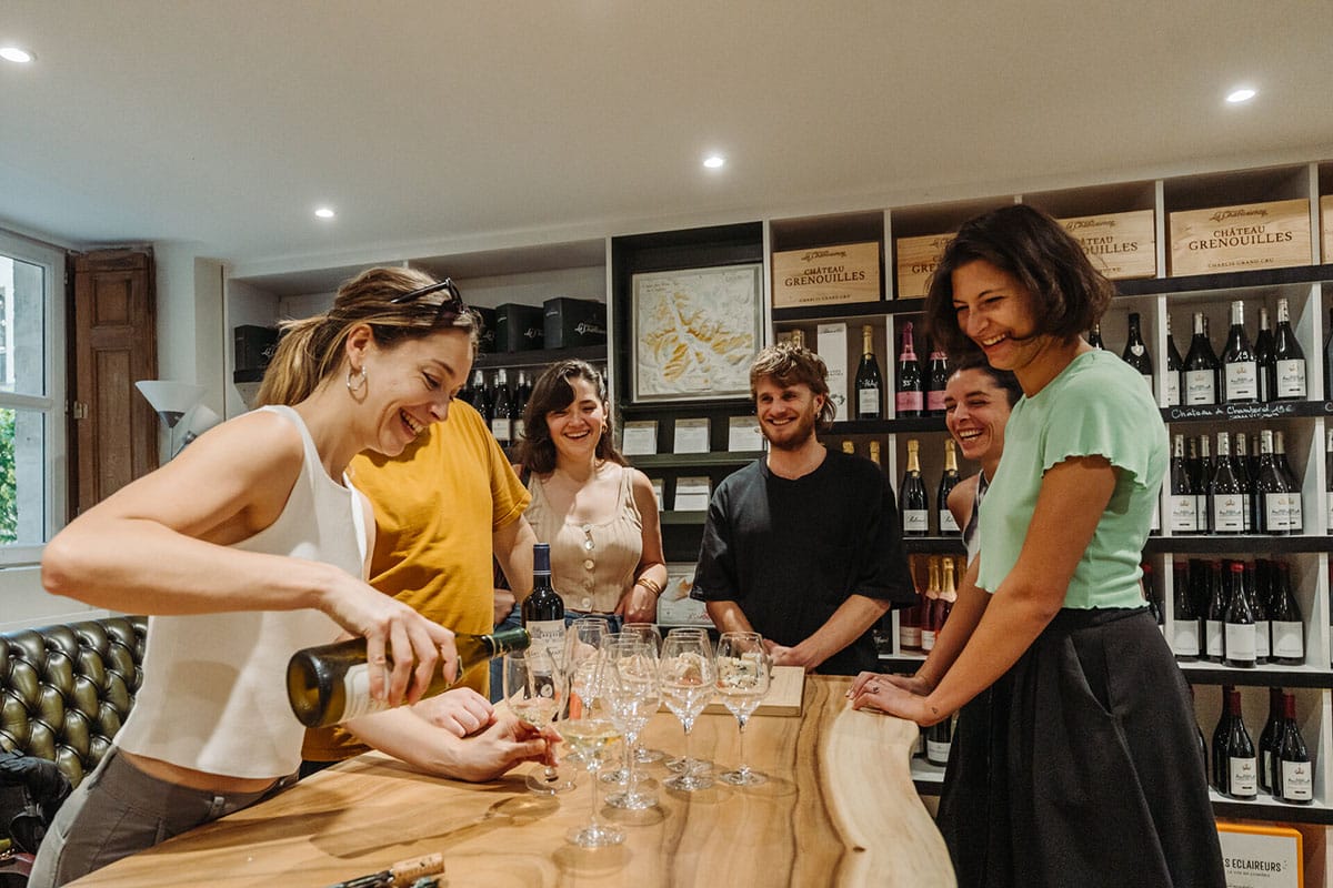 group of people pouring wine at a table and smiling.
