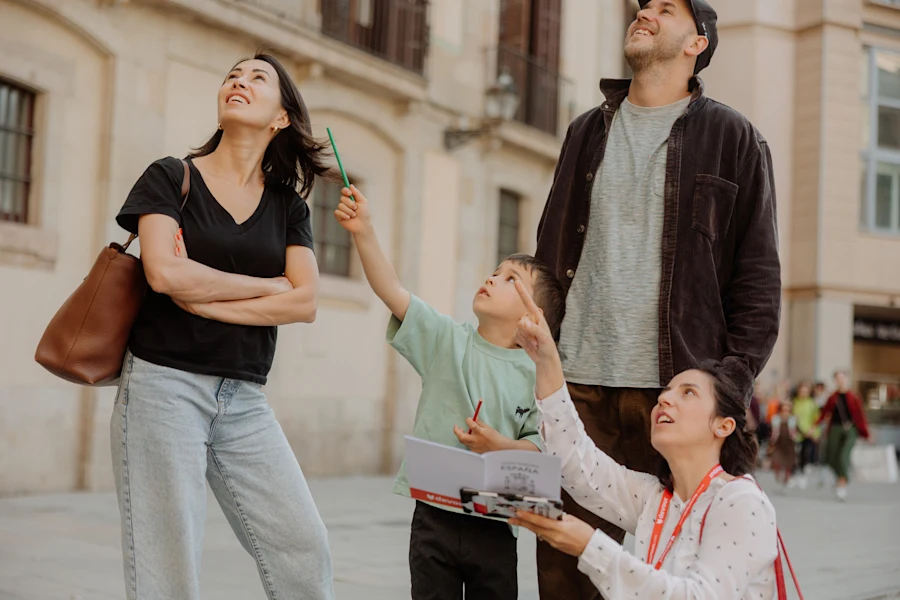 A tour guide points upward while a young boy and his parents look up at historic architecture in Barcelona.