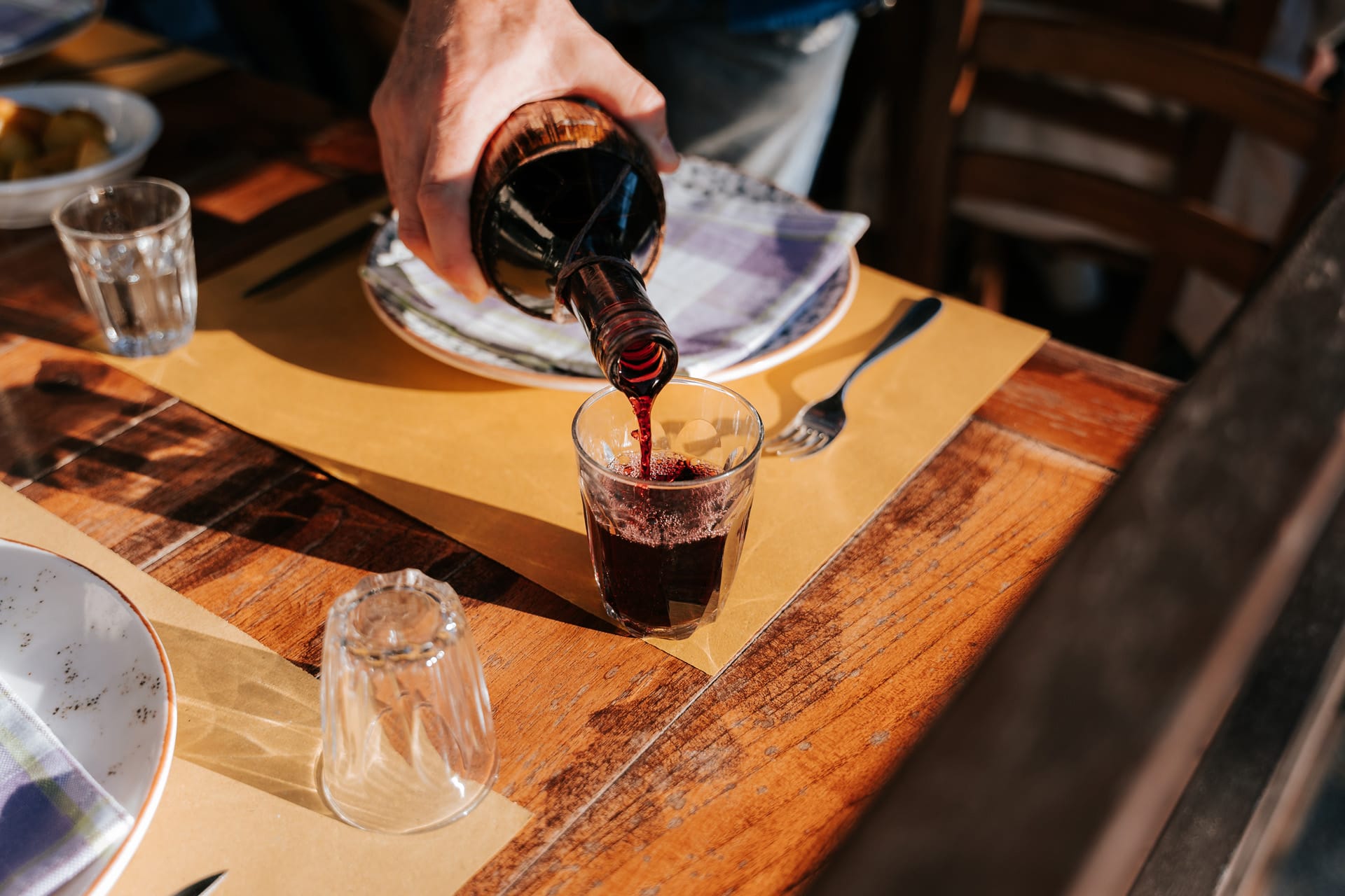 pouring red wine into a stemless glass.