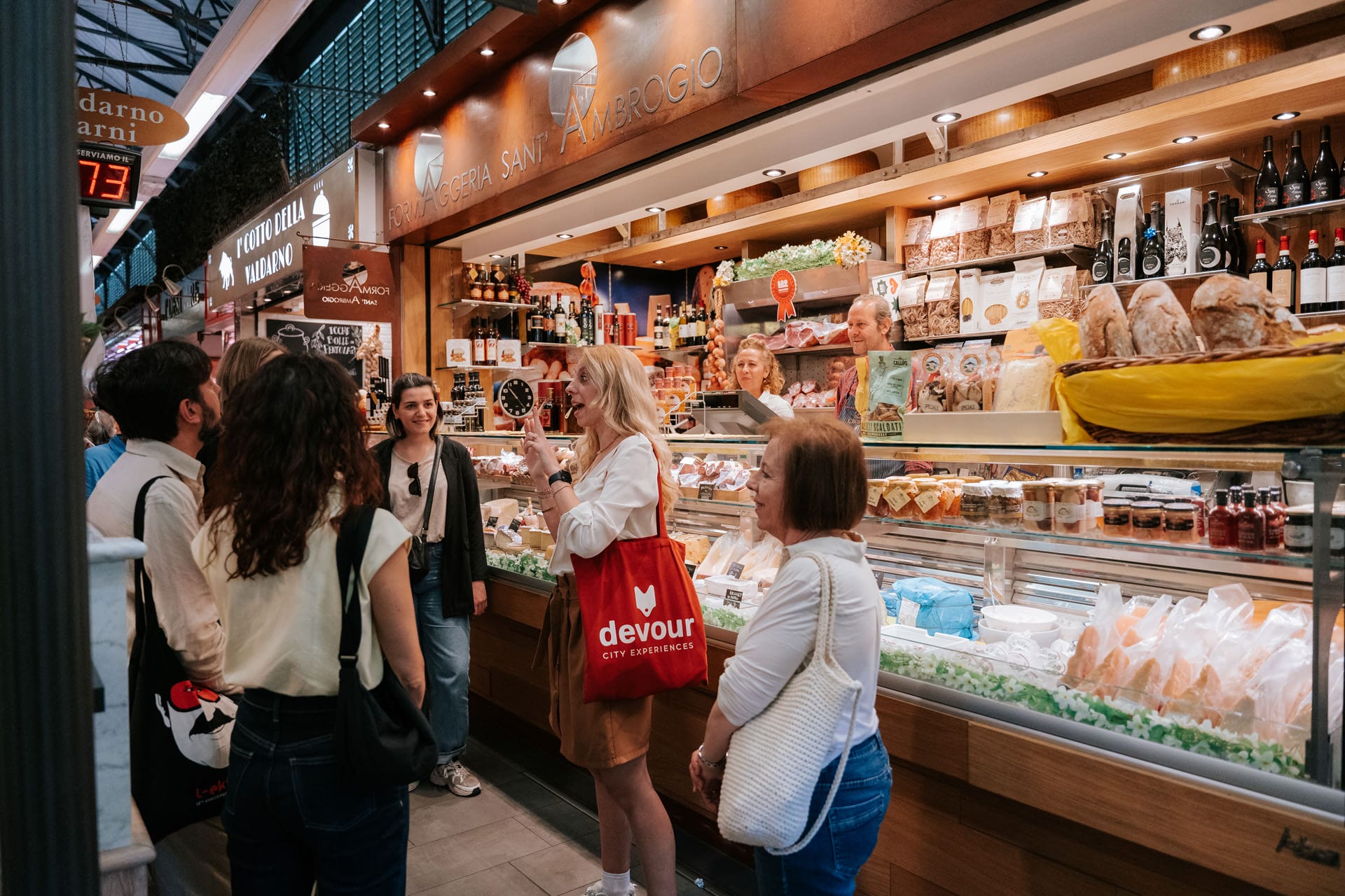 female tour guide talking to a group in front of a food market stall.