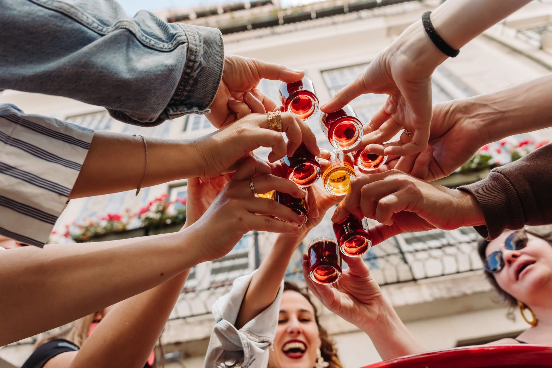 people toasting with small glasses of ginjinha, sour cherry liqueur.