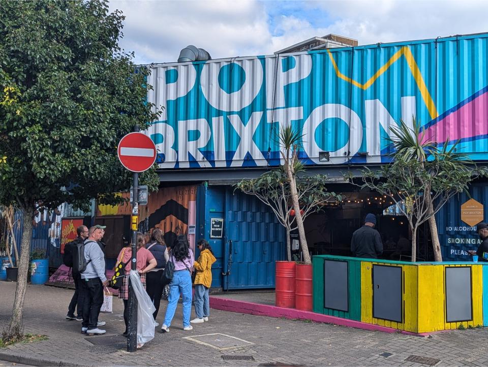 A tour group outside of the Brixton market, which is painted a bright sade of blue with pops of color