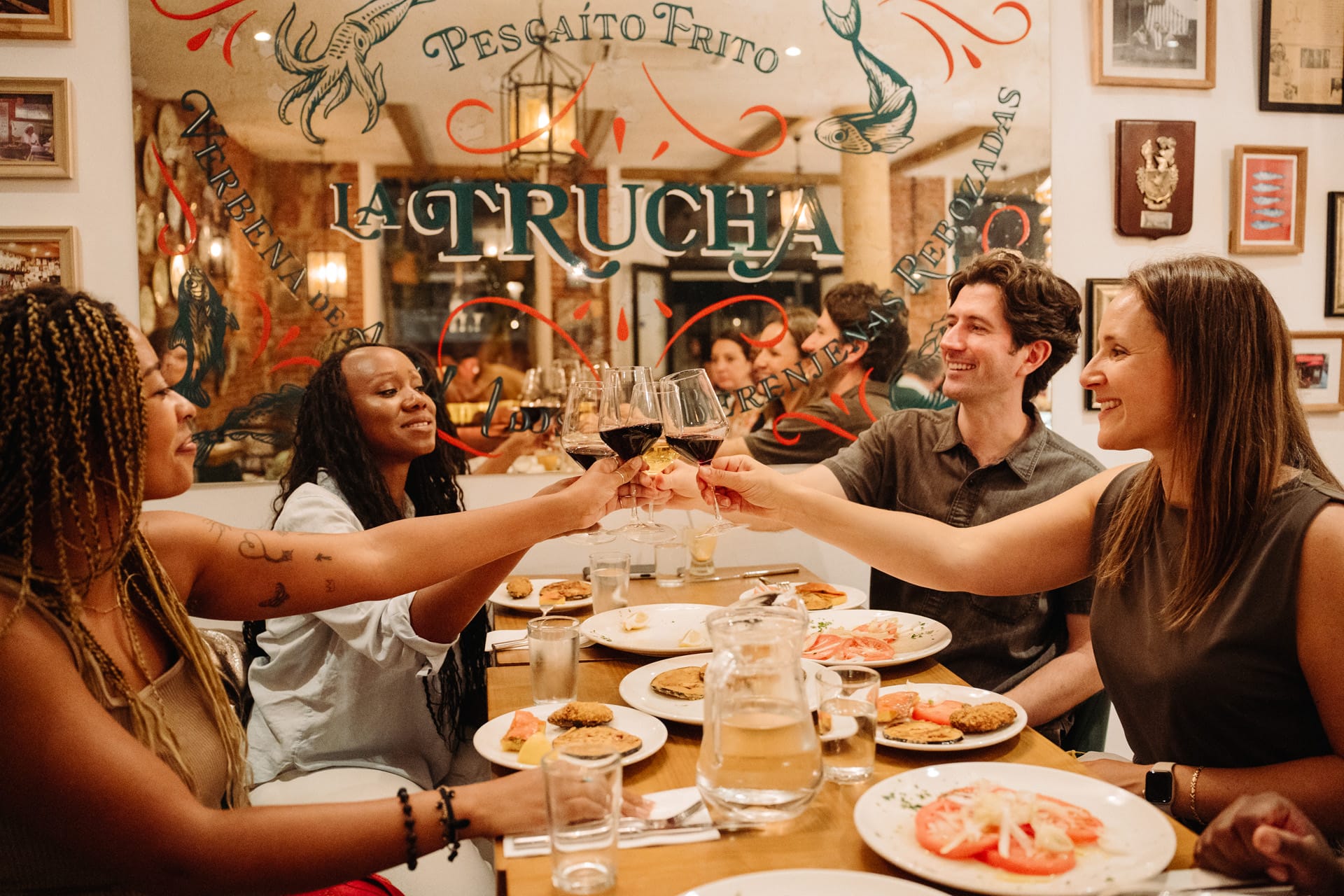 people toasting with wine glasses at a table of tapas in Madrid.