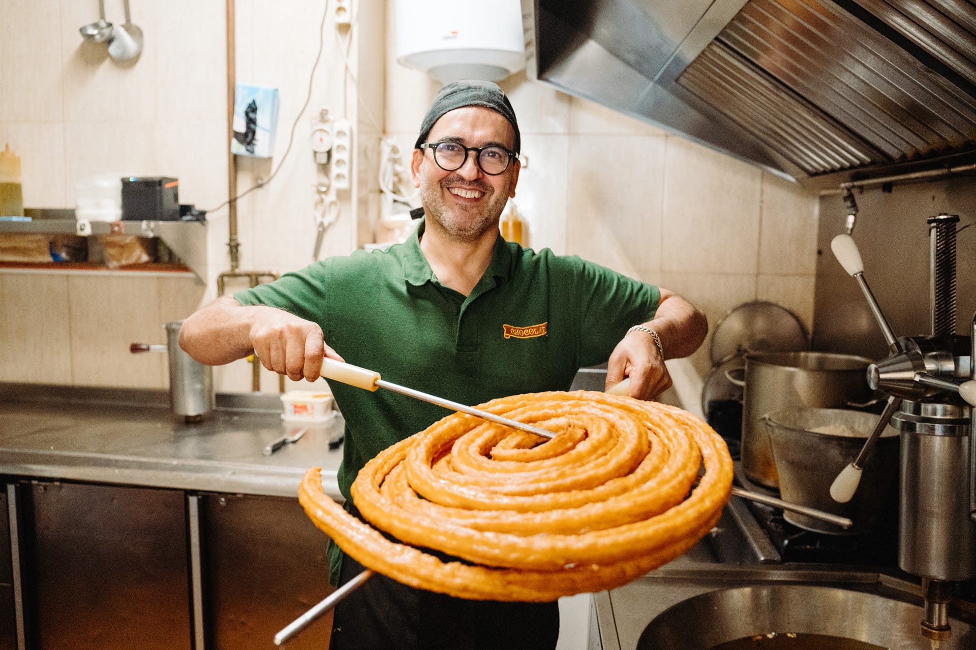 man holding a large churro that was just taken out of the hot oil.
