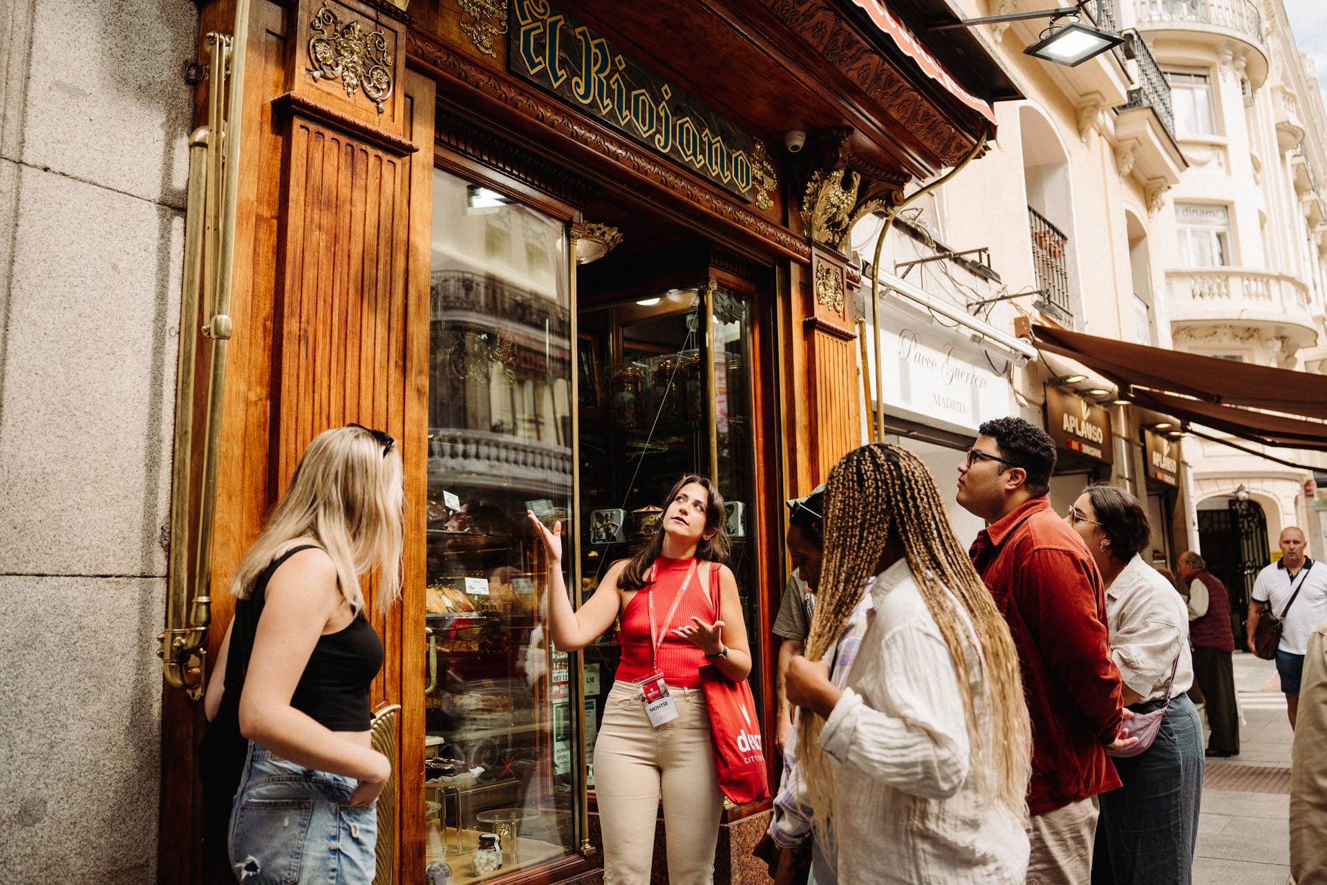 tour guide telling a group about a shop with a sign reading "El Riojano" above the door.