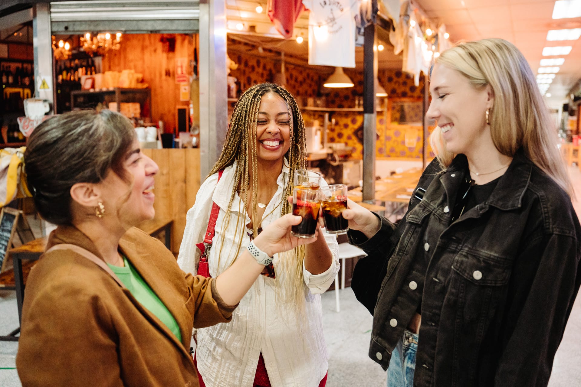 three ladies toasting with small glasses and smiling.