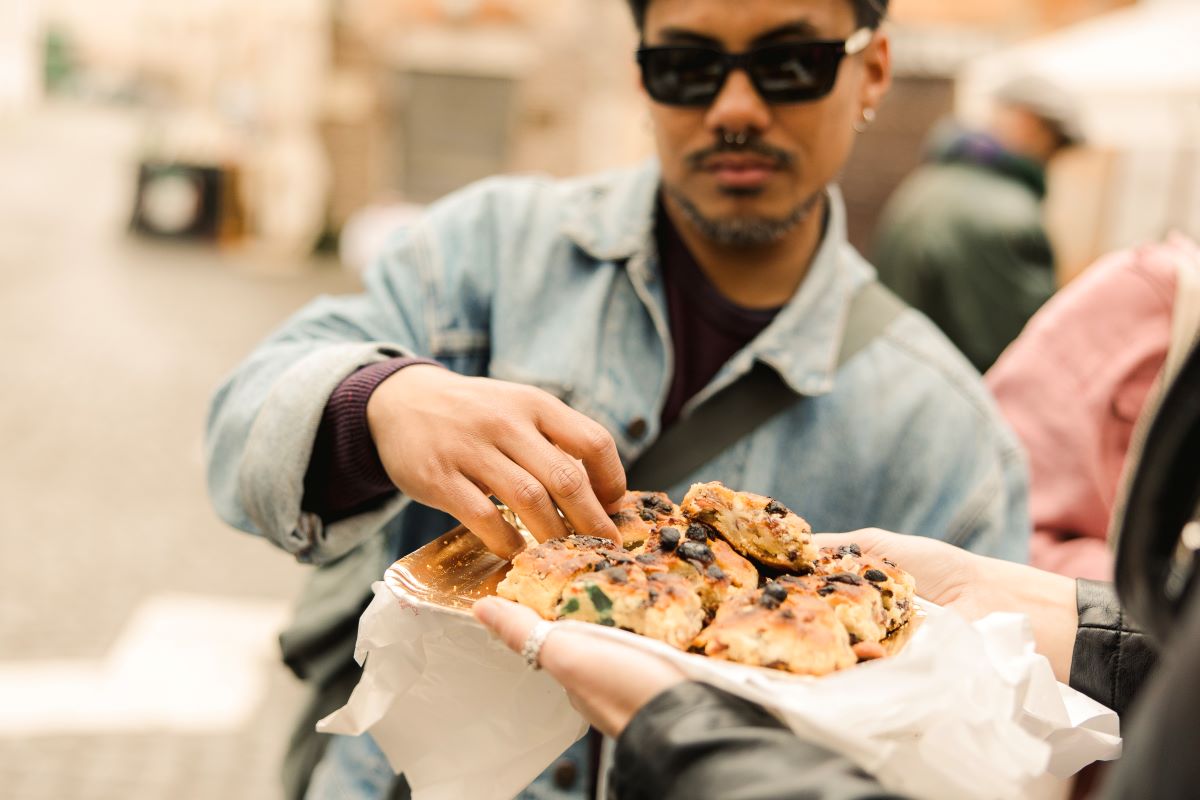 A man taking a piece of Italian bread from a tray. 