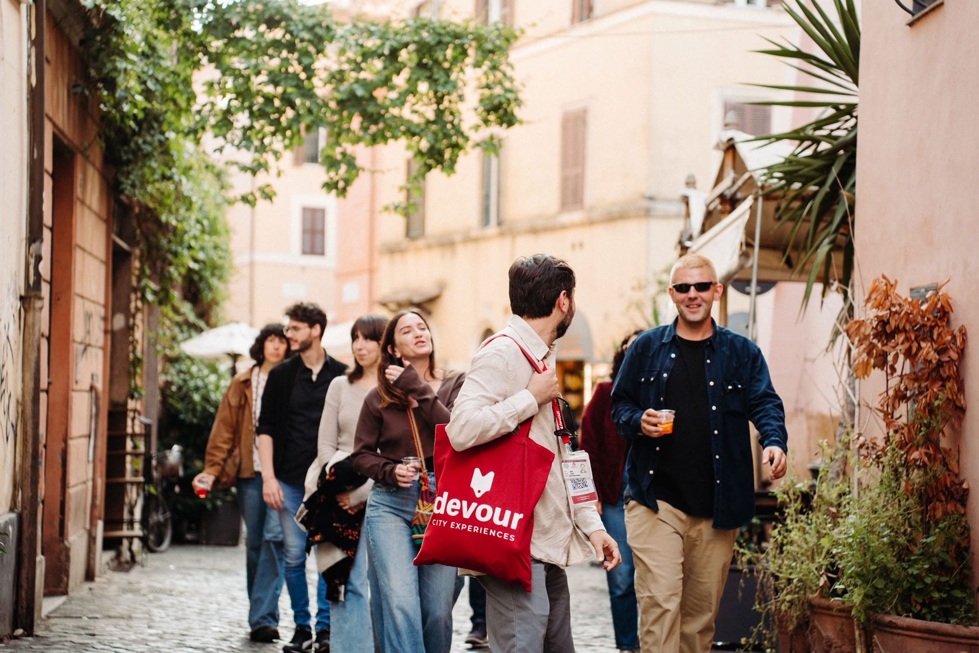 A guide leads a small group of people through a charming cobblestone street lined with colorful buildings.