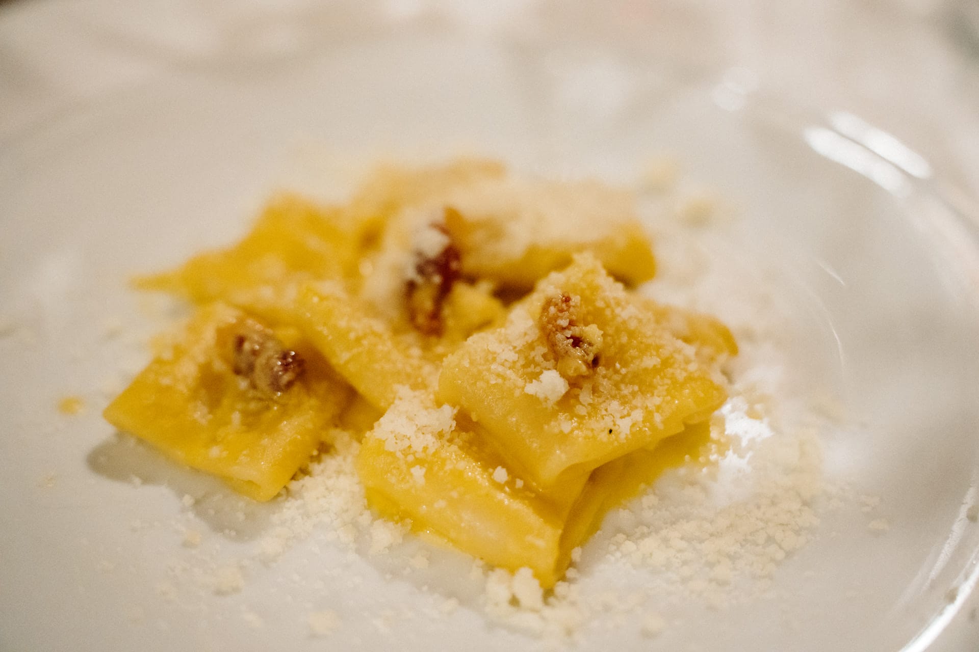 A close-up of a plate of fresh pasta sprinkled with pecorino cheese and crispy guanciale.