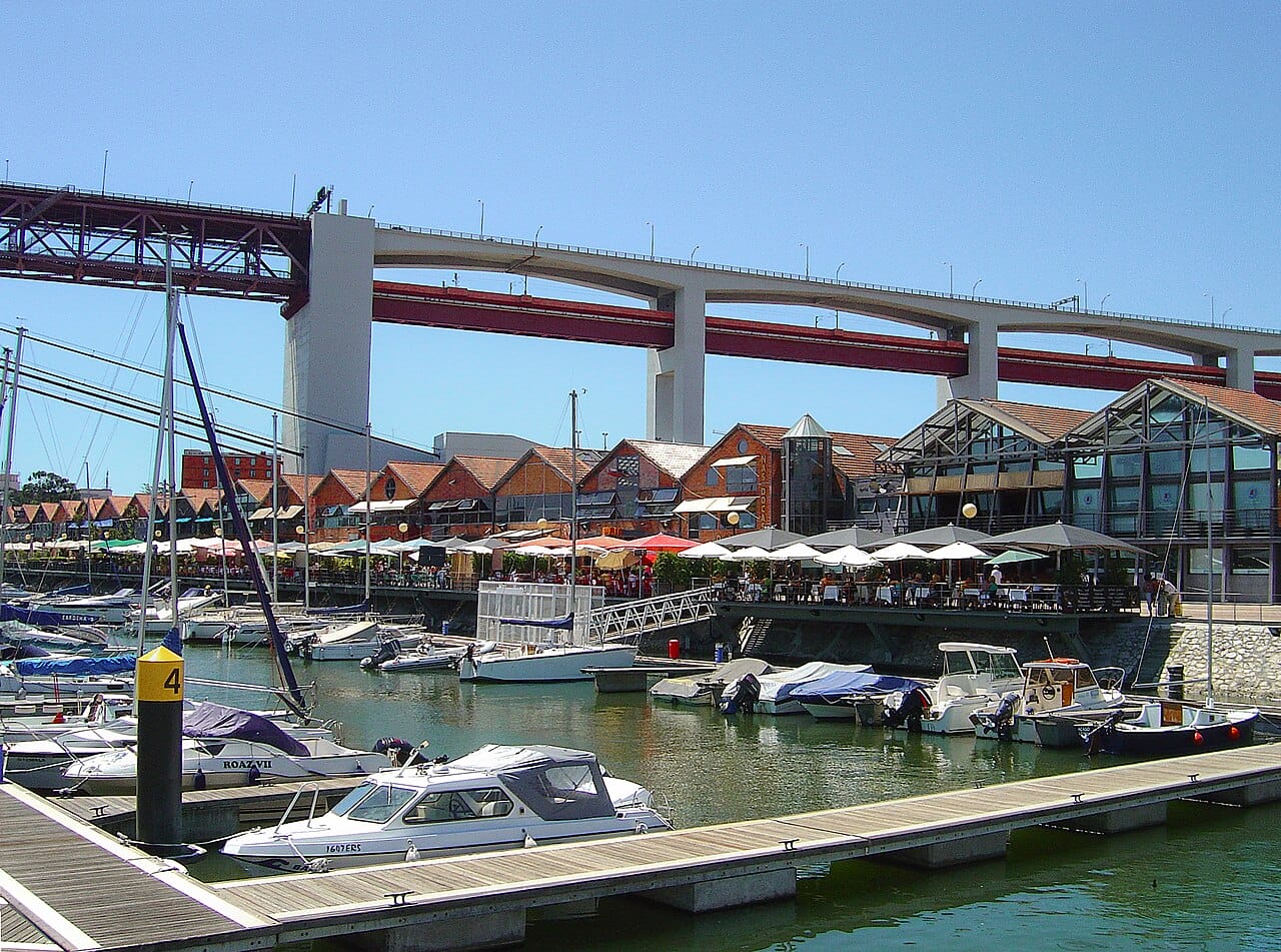 small boats at a dock with a car bridge going over the water.