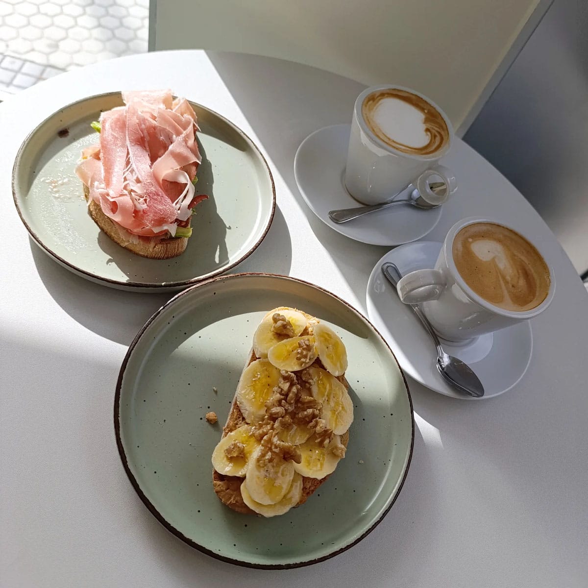two coffee cups and two slices of toast with fruit and other toppings.