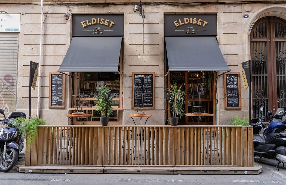 wooden patio off of a brick building with windows and black awnings.