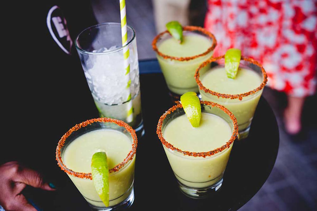 a tray of four avocado passionfruit margaritas with a glass of ice.
